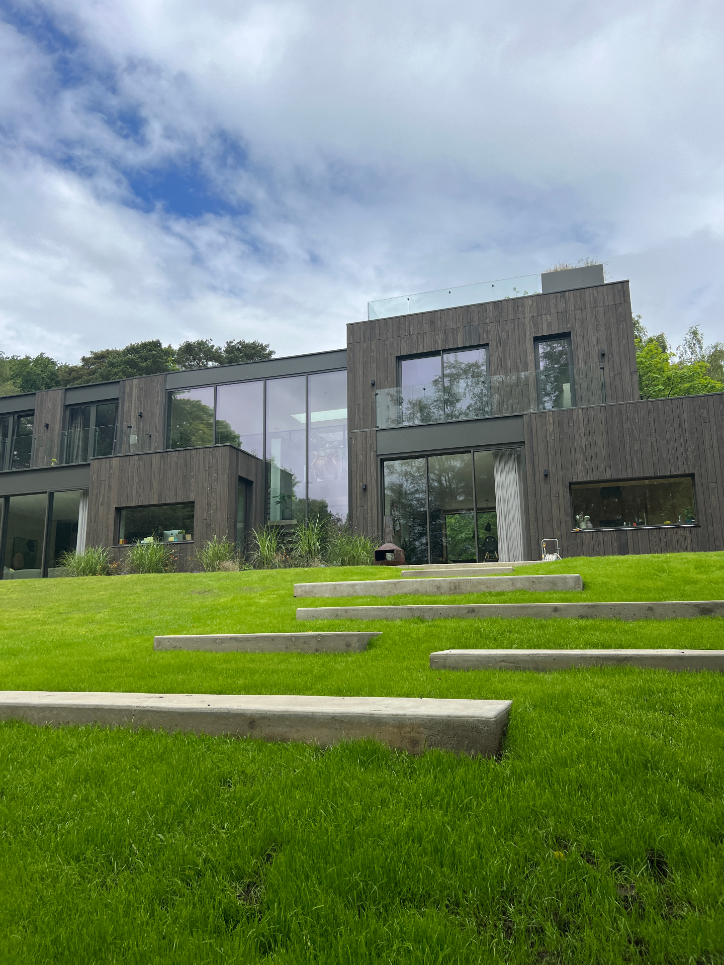 Wide view of the contemporary timber house with the concrete step cascade in the foreground