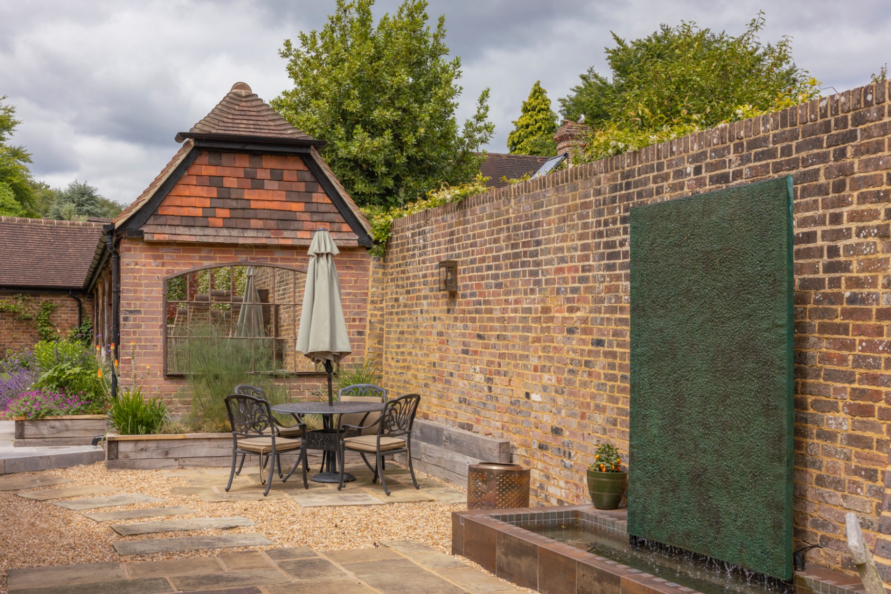 Wide view of the courtyard with the lava water wall set into aged brick and a sunken tiled rill