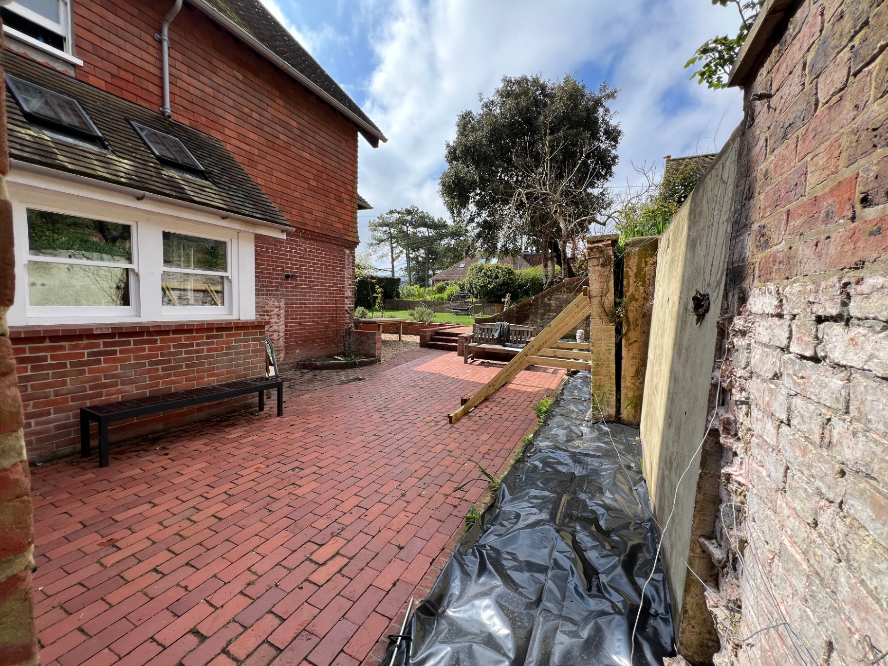 Original courtyard — narrow side passage with exposed brick wall and black sheeting