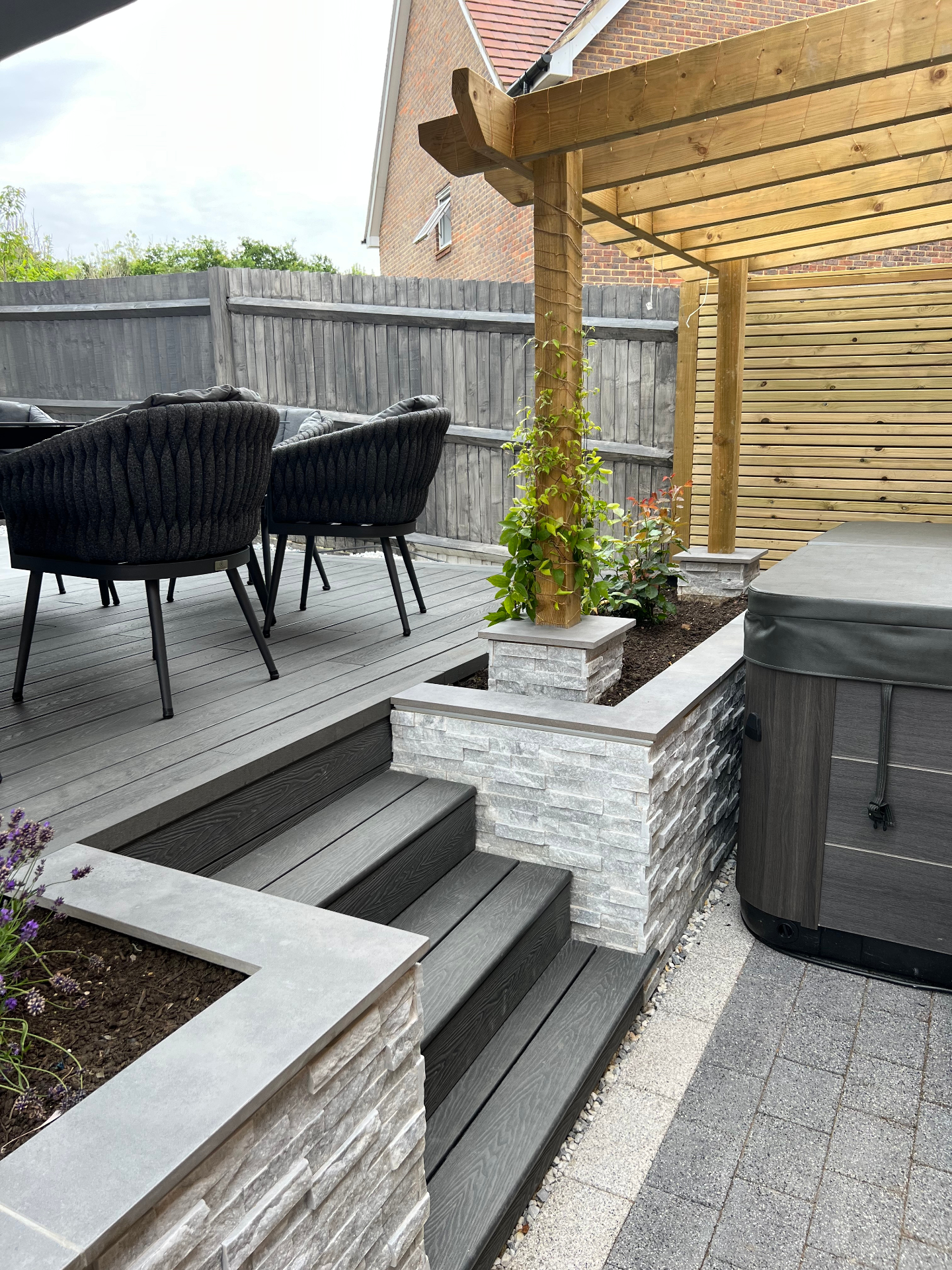 Finished garden — composite steps, crisp stone copings and pergola posts beside the spa terrace