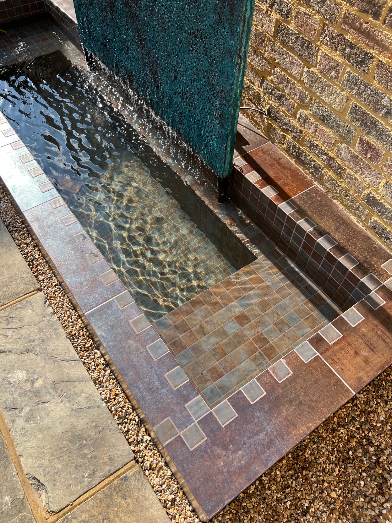 Close detail of water sheeting down the lava wall into the mosaic-tiled rill