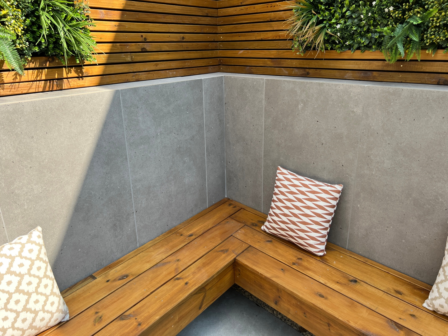 Detail of corner seating, porcelain wall cladding and cedar screen with planted panels