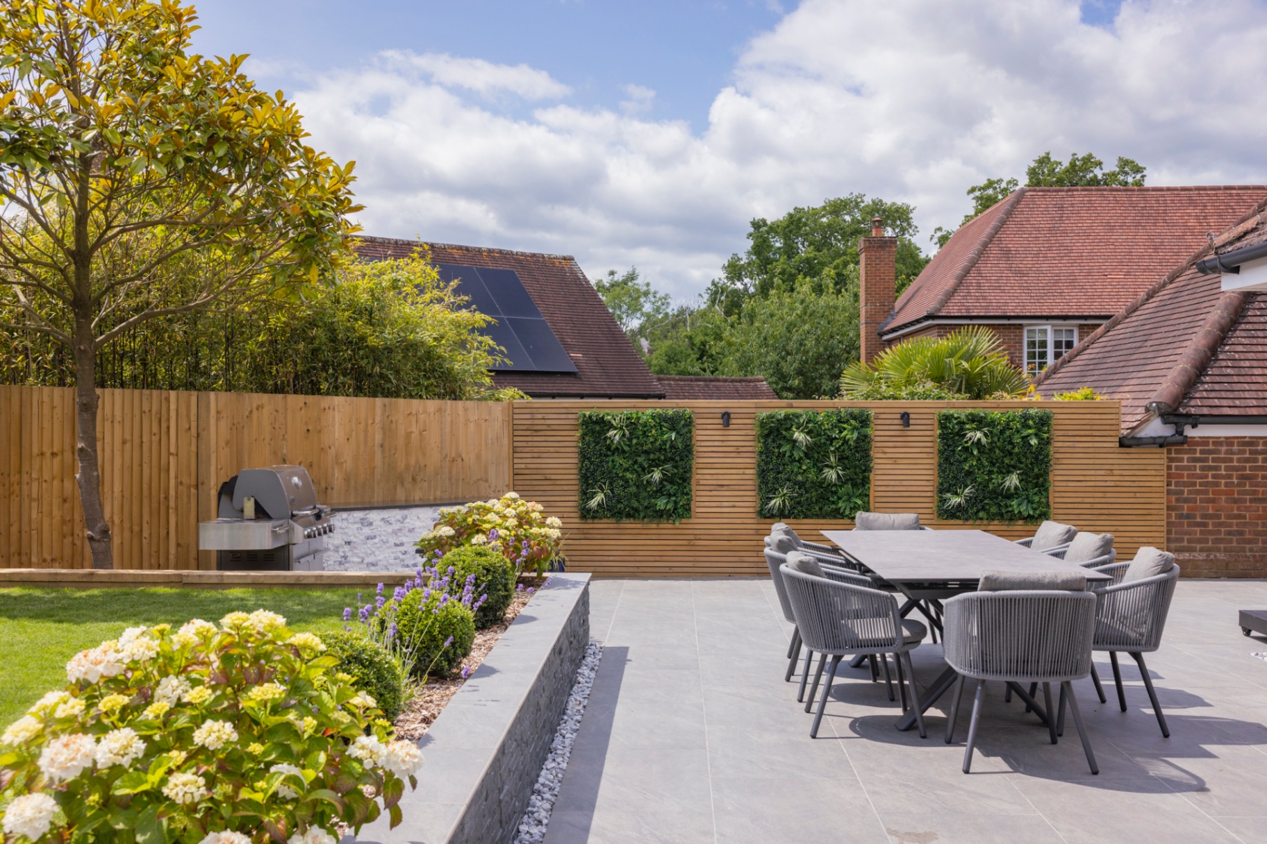 Wide view of porcelain patio, raised slate planter and cedar-clad screen wall