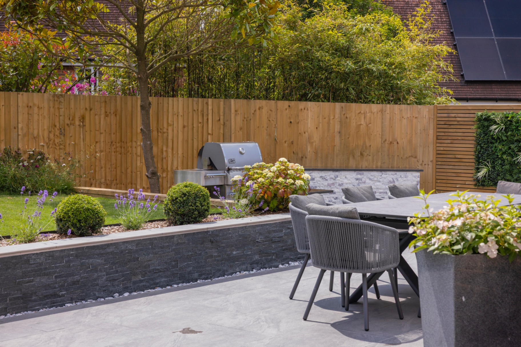 Dining terrace with lavender, hydrangeas and topiary along the slate wall
