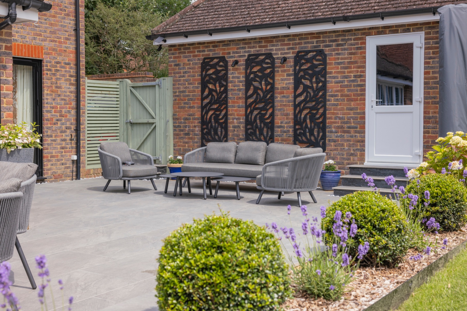 Outdoor lounge on porcelain paving with decorative wall screens and lavender borders