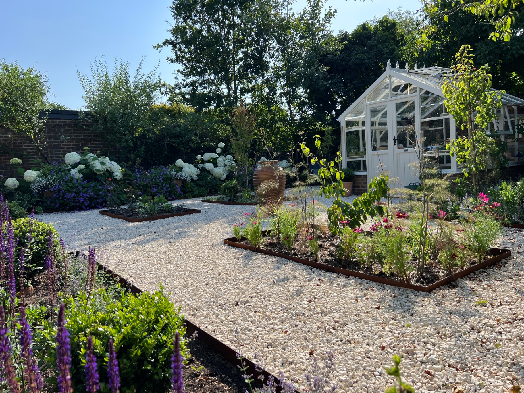 Walled flower garden — gravel pathways, corten-edged beds and a traditional white glasshouse